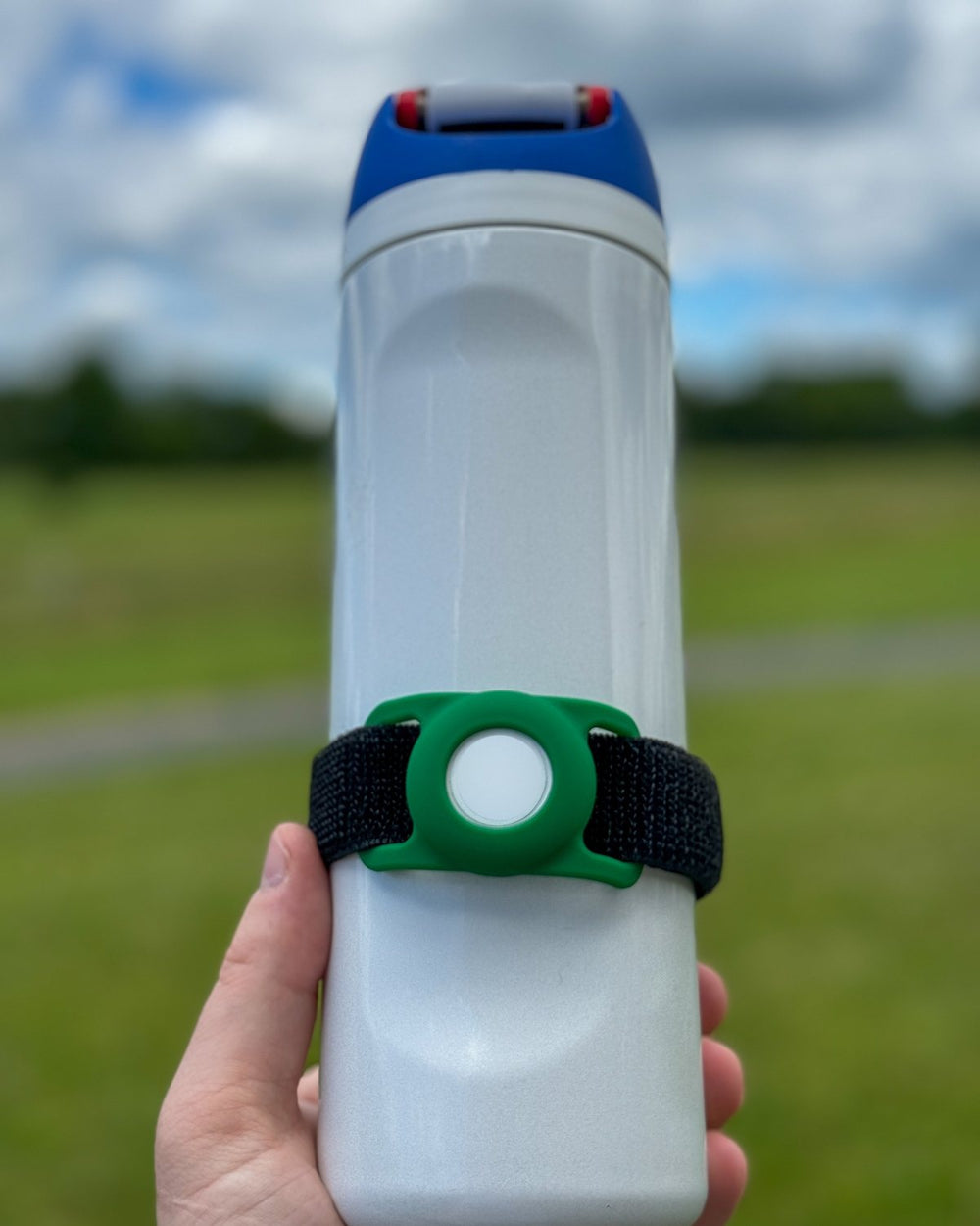 A green Bottle Beacon with an AirTag on a white sport bottle