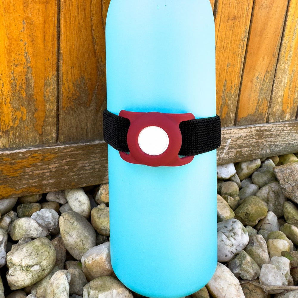 Maroon Bottle Beacon strap holding an Apple AirTag on a light blue Owala FreeSip bottle